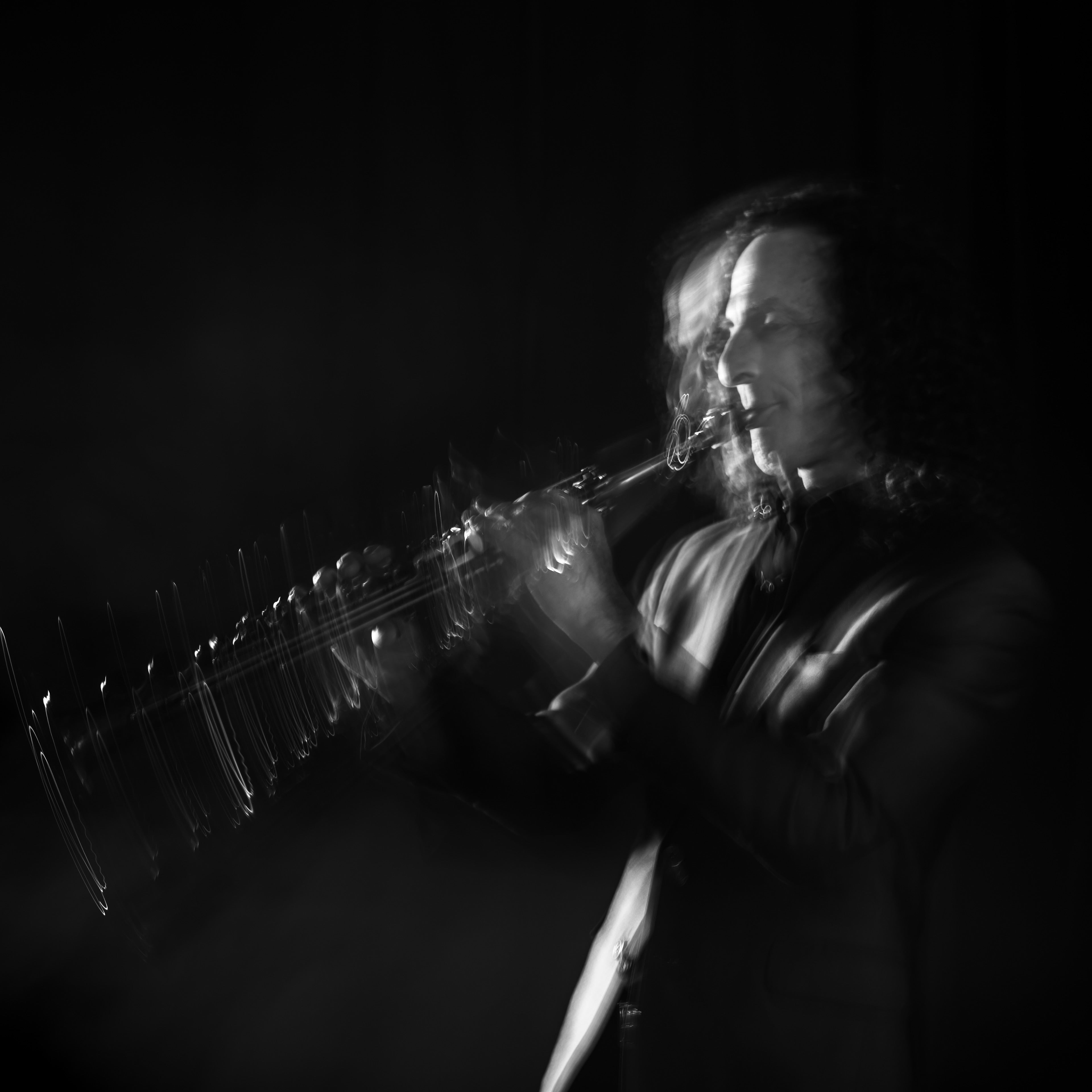 Black and white blurry action photo of Kenny G playing his instrument